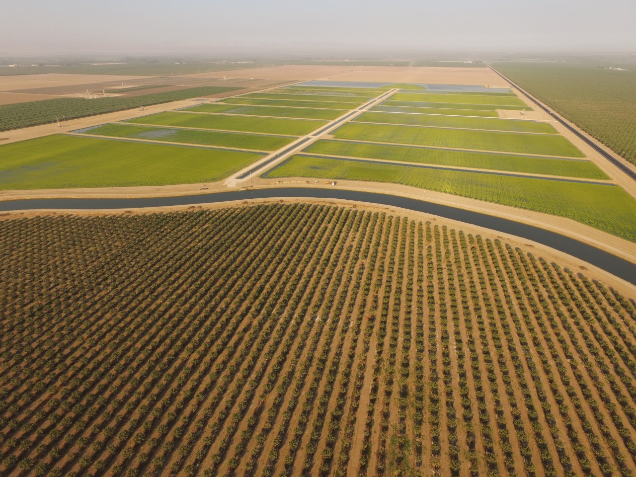 Aerial view of a field showcasing a complex irrigation system with water channels and crops in the surrounding area.