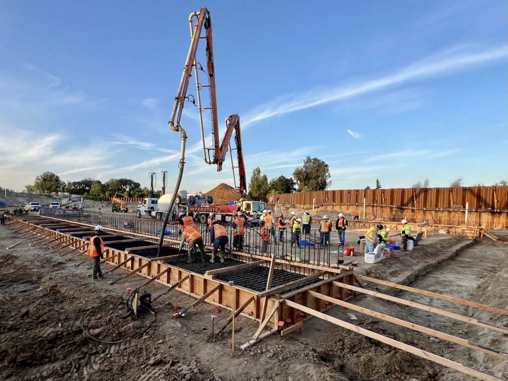 A concrete pump with an extension arm is used to place concrete for the river bypass channel.